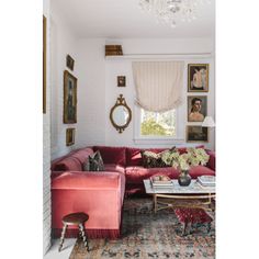 a living room with red couches and pictures on the wall above them, along with a chandelier