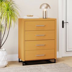 a wooden chest of drawers next to a potted plant