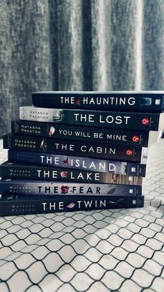 a stack of books sitting on top of a white tiled floor next to a curtain