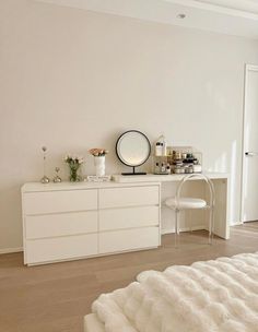 a white bedroom with a dresser and mirror