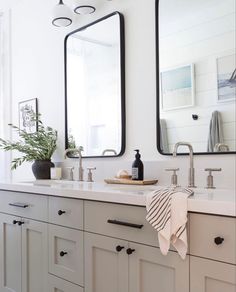 a bathroom with two sinks and mirrors on the wall next to it is a potted plant