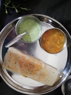 a silver plate topped with food and dipping sauces