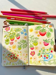 an open notebook with drawings and colored pencils