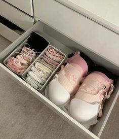 several pairs of slippers are in the drawer on the floor next to some drawers