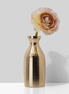 a gold vase with a pink flower in it