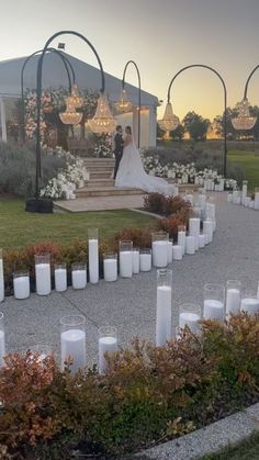 a bride and groom standing in front of their wedding ceremony venue with candles on the ground