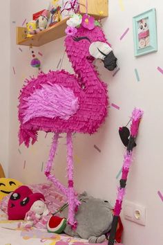 a pink flamingo standing on top of a bed next to a shelf filled with stuffed animals