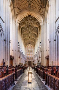 the inside of a large cathedral with pews and stained glass windows on both sides