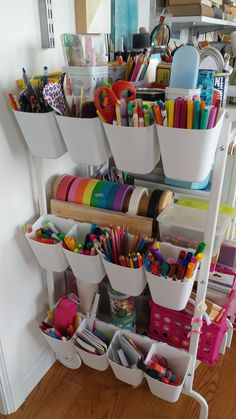 a white shelf filled with lots of crafting supplies on top of a hard wood floor