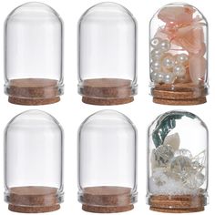 four glass jars with sand, shells and flowers in them sitting on top of each other