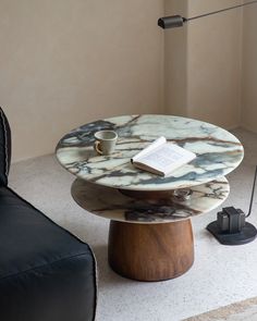 a marble coffee table with a book on it and a lamp in the corner next to it