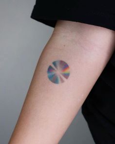 a woman's arm with a colorful circle tattoo on the left side of her arm