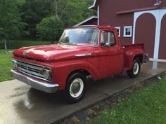 an old red truck parked in front of a barn