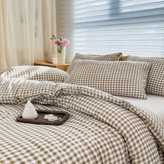 a bed with brown and white checkered comforter, pillows and pillow cases on it