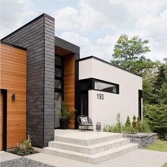 a modern house with black and white siding on the front door, steps leading up to it