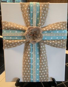 a white box with blue ribbon and a flower on it sitting on a black table