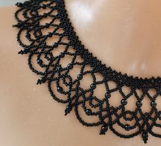 a black beaded necklace is displayed on a mannequin's neckline