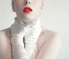 a woman with red lipstick and white gloves on her face is posing for the camera