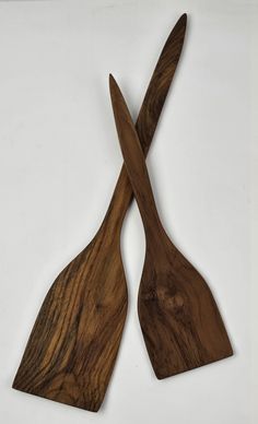 two wooden utensils made out of wood sitting side by side on a white surface