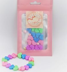 a pink bag filled with lots of colorful hearts next to a string of small beads