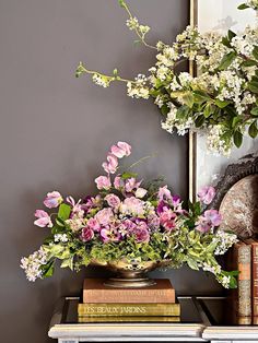 a vase filled with pink and white flowers on top of a table next to books