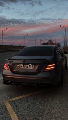 the back end of a car parked in a parking lot at dusk with its lights on