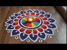 a candle is lit in the middle of a colorful flower design on a wooden floor