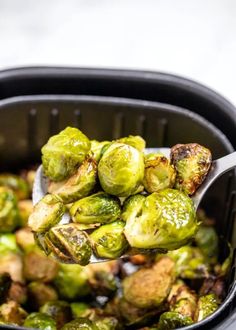 the brussel sprouts are being spooned out from an air fryer