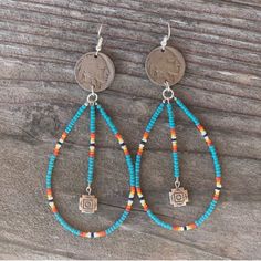 the turquoise and orange beaded hoop earrings are hanging from a wooden plank with a penny