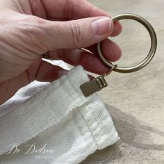 a person holding onto a ring on top of a white towel with a gold colored handle