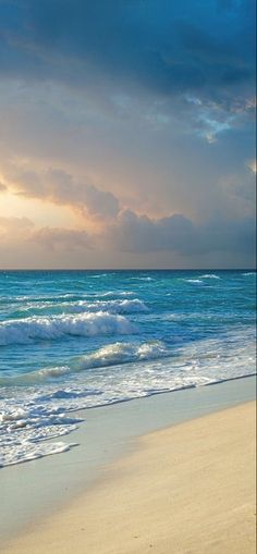 an ocean beach with waves coming in to shore and the sun shining down on the water