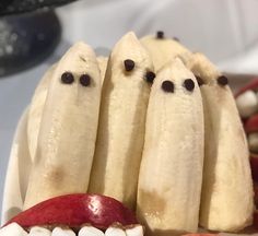 bananas with faces are arranged in the shape of ghost heads on top of an apple