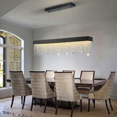 a dining room table and chairs with chandelier hanging from the ceiling over it