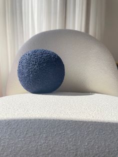 a blue ball sitting on top of a white bed