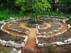 a circular garden design made out of rocks and stones with a tree in the middle