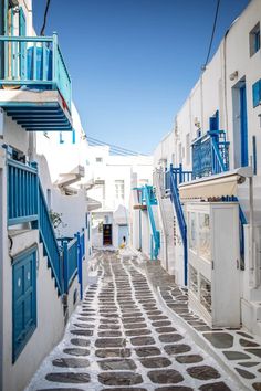 an alley way with white buildings and blue shutters