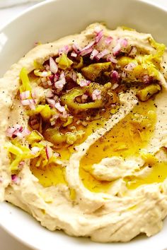 a white bowl filled with hummus and onions