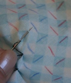 someone is stitching something on the fabric with a pair of scissors in their hand