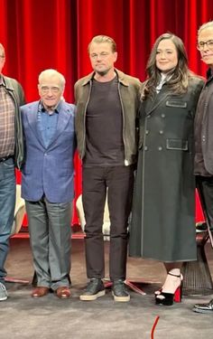 four people standing in front of a red curtain