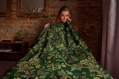 a woman is wrapped in a green floral blanket