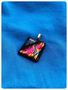 a colorful pendant is sitting on a blue cloth