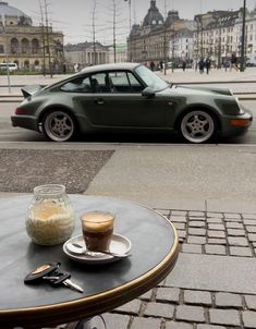 a cup of coffee sitting on top of a table next to a parked car