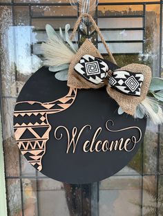 a welcome sign hanging on the front door with burlocks and feathers attached to it