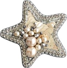 a star shaped brooch with pearls and other things in it's center, on a white background