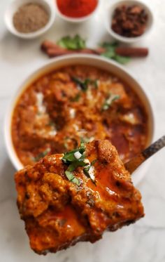 a white bowl filled with meat and sauce