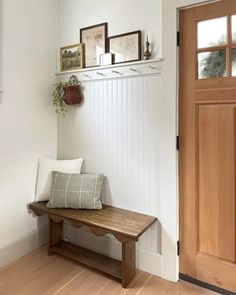 a wooden bench sitting in front of a door next to a wall mounted planter