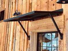 a close up of a metal shelf on the side of a wooden building with a window