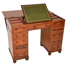 an antique wooden desk with drawers and a green leather pad on it's top