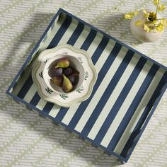 a blue and white striped tray with figurines in it next to a flower vase