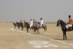 several people are riding horses in the desert